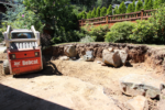 A machine moves boulders around in a yard