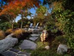 Stone steps lead to a patio, with two chairs and a fire pit