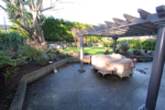 Before shot: a backyard area with an overhang and covered tables and chairs