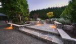 Wide stone steps lead to a patio with a table and chairs